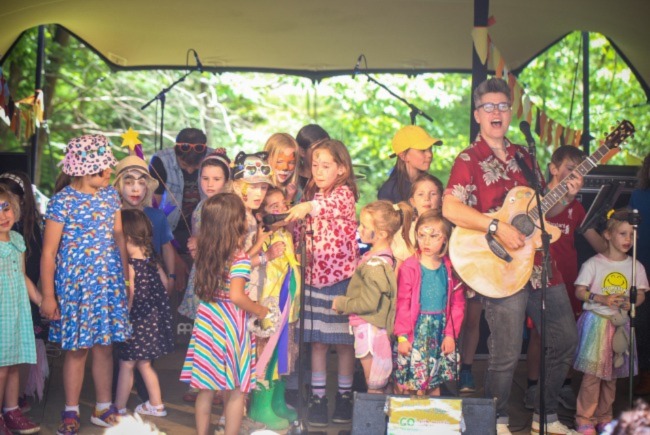 Musician Al Start singing on stage with children at Elderflower Fields Festival near Brighton. 